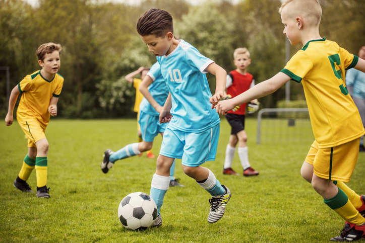 Two boys soccer teams competing for the ball during a football match